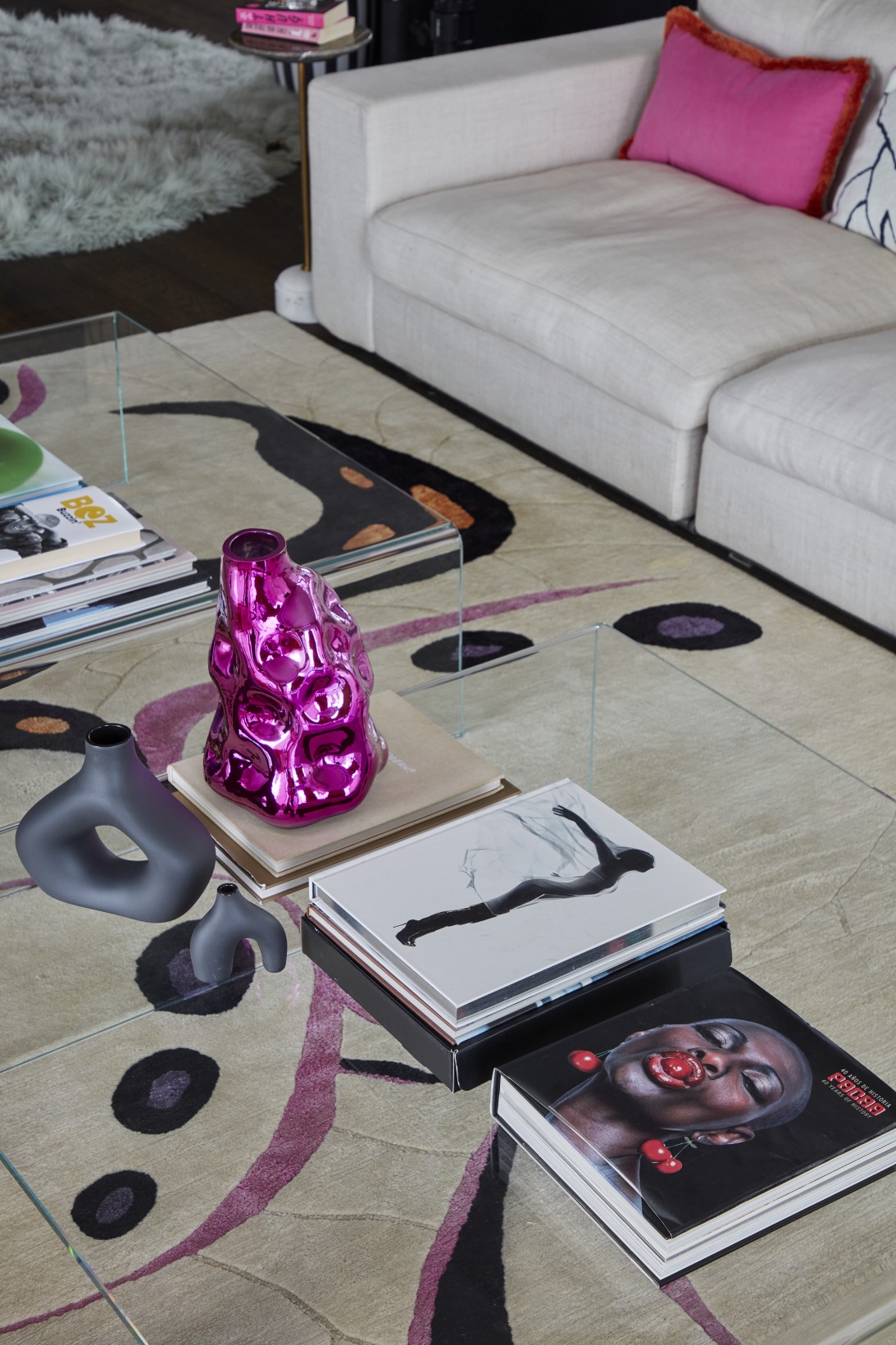 Colourful glassware, sculptural vases, and art books on coffee table in London penthouse media room