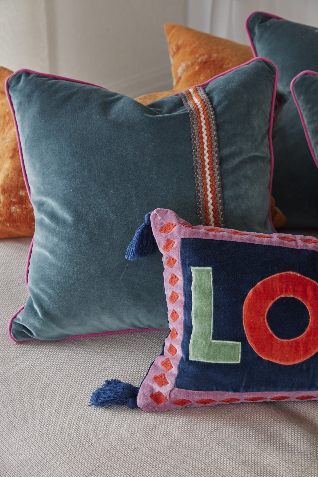 Colourful velvet cushions in teal and coral with love motif in London penthouse media room