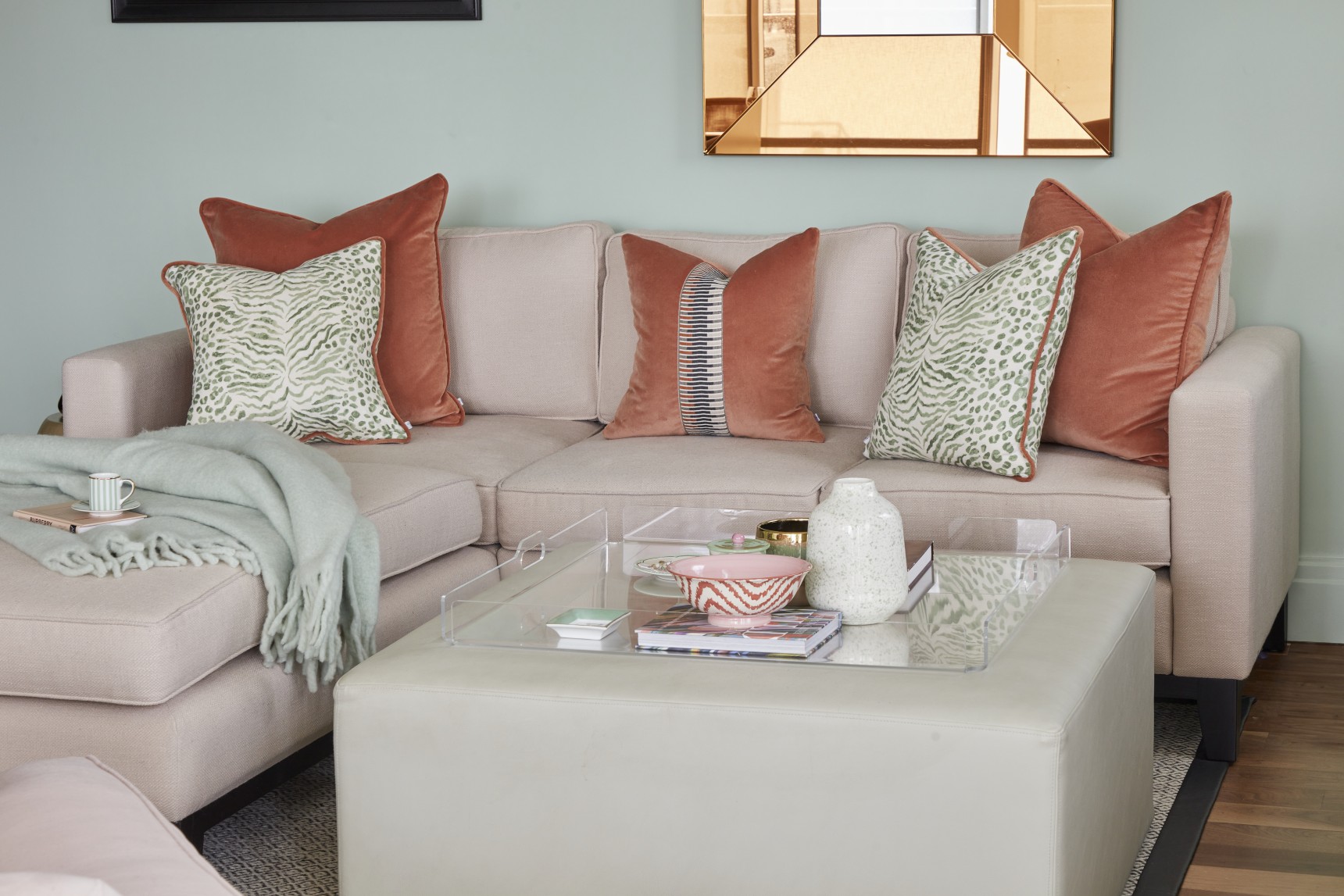 Luxury penthouse lounge with corner sofa, warm terracotta cushions, and statement mirror