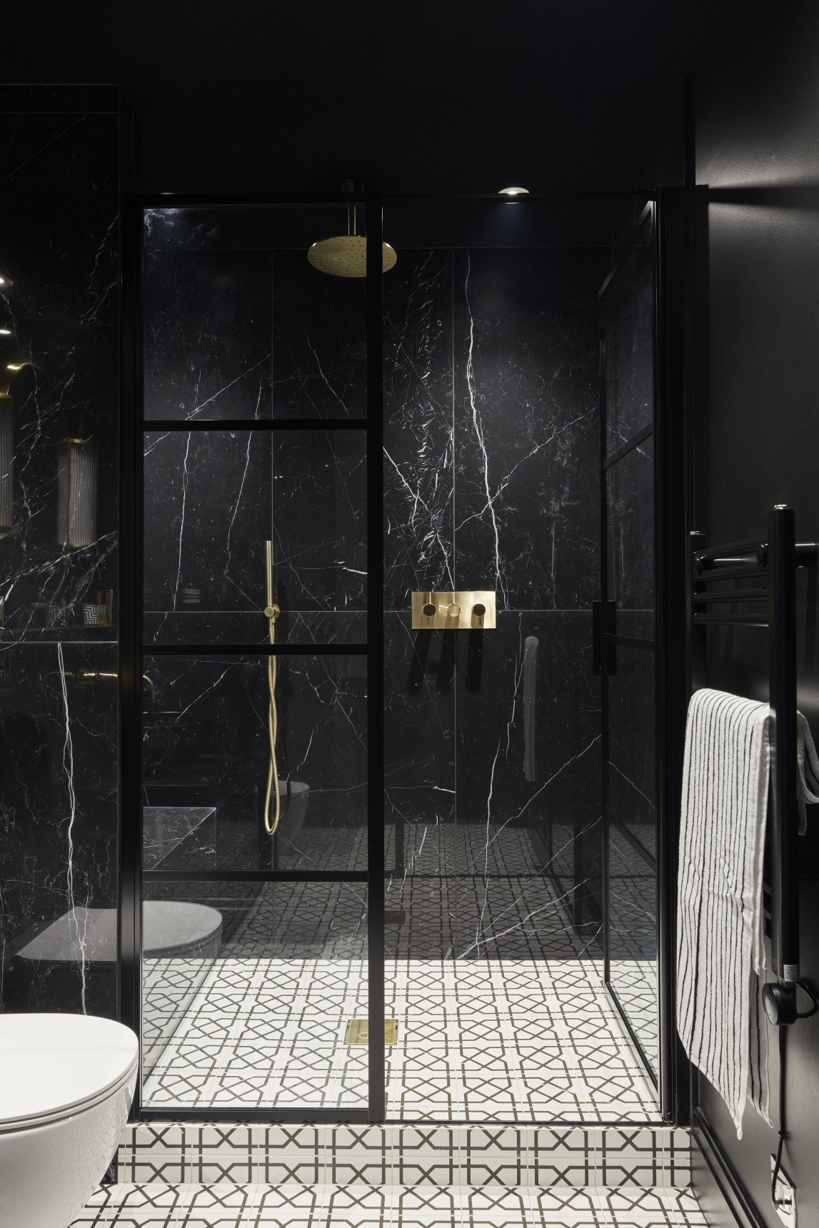 Luxury penthouse shower room with black marble walls, gold fixtures, and patterned floor tiles