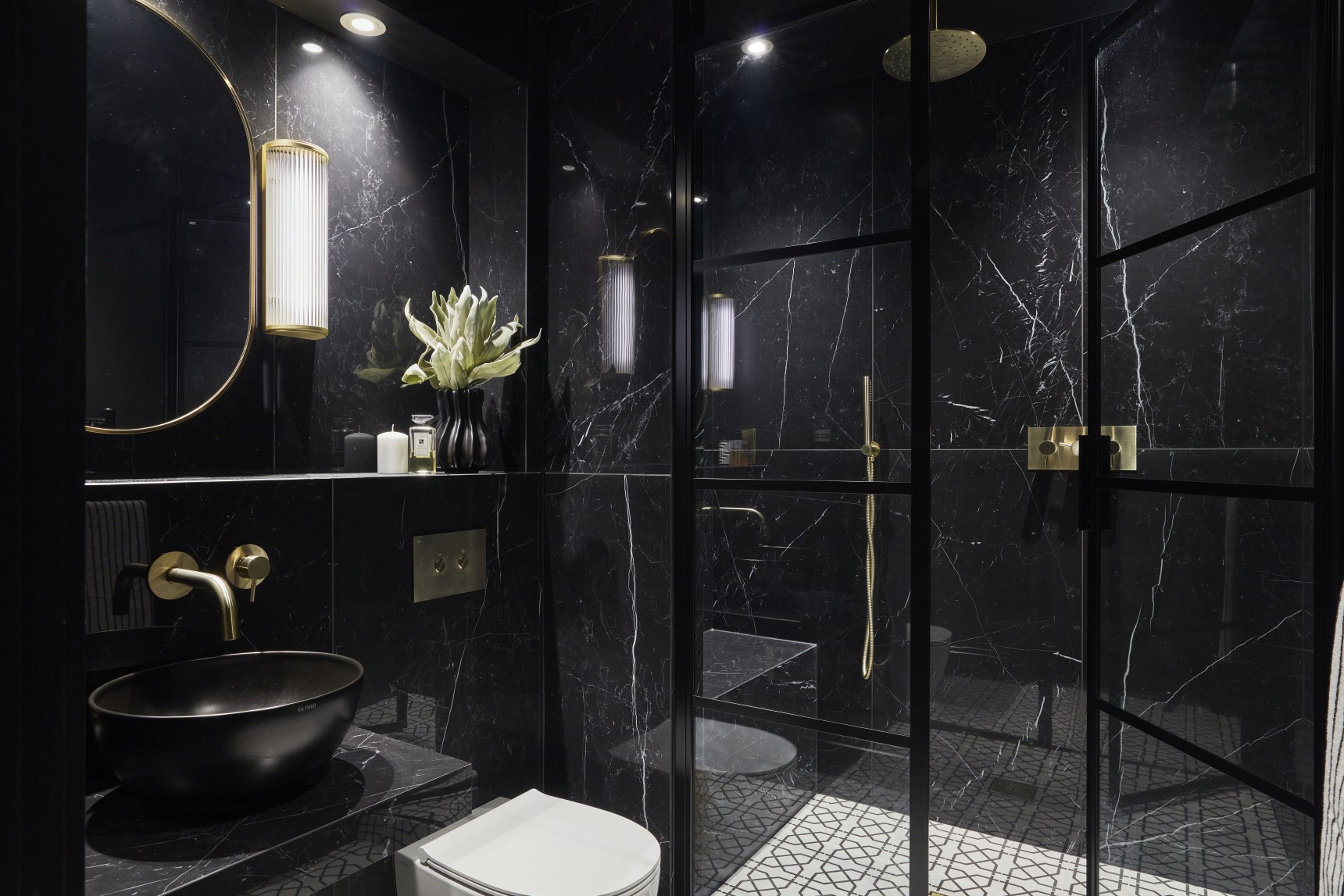 London penthouse shower room with black stone, gold fittings, and oval mirror