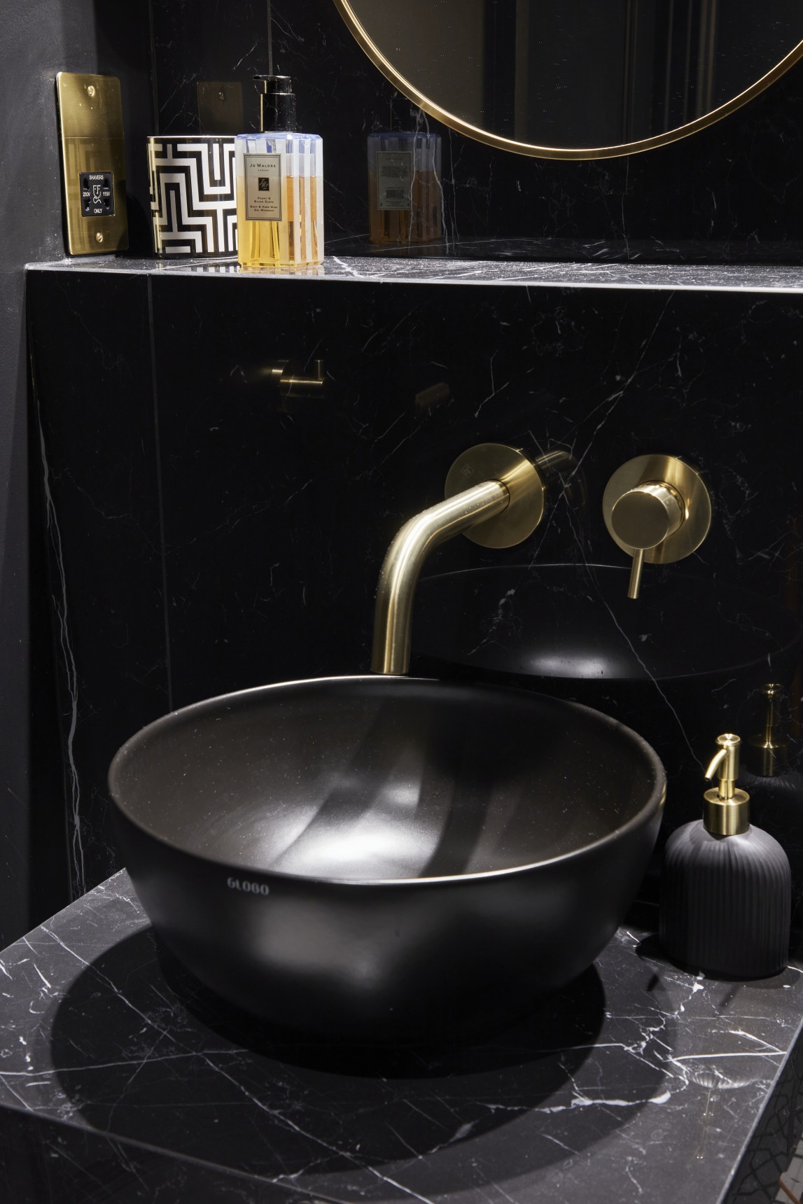 Black countertop basin with gold wall-mounted tap in luxury penthouse bathroom