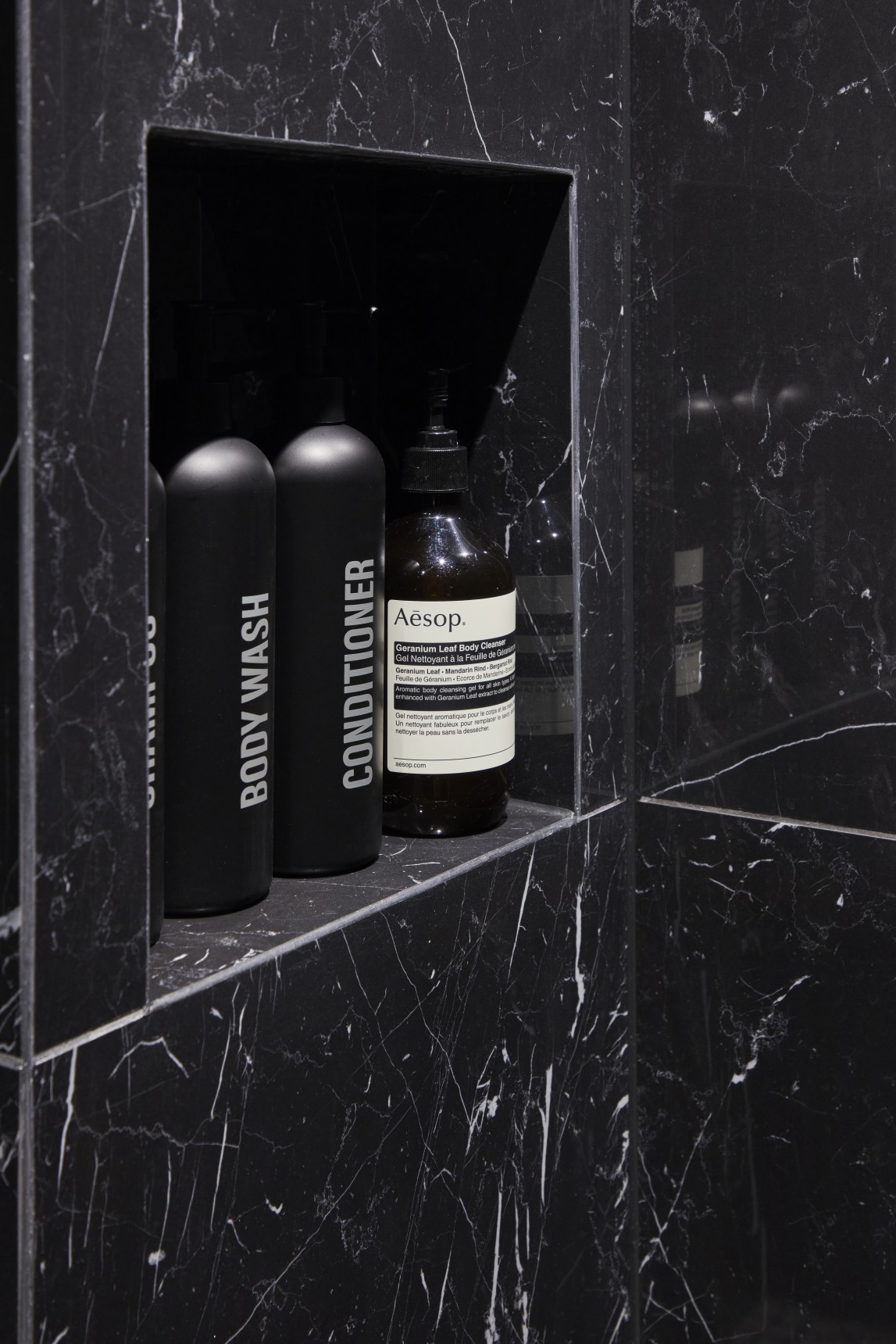 Built-in shower niche in black marble with Aesop and luxury toiletries, London penthouse