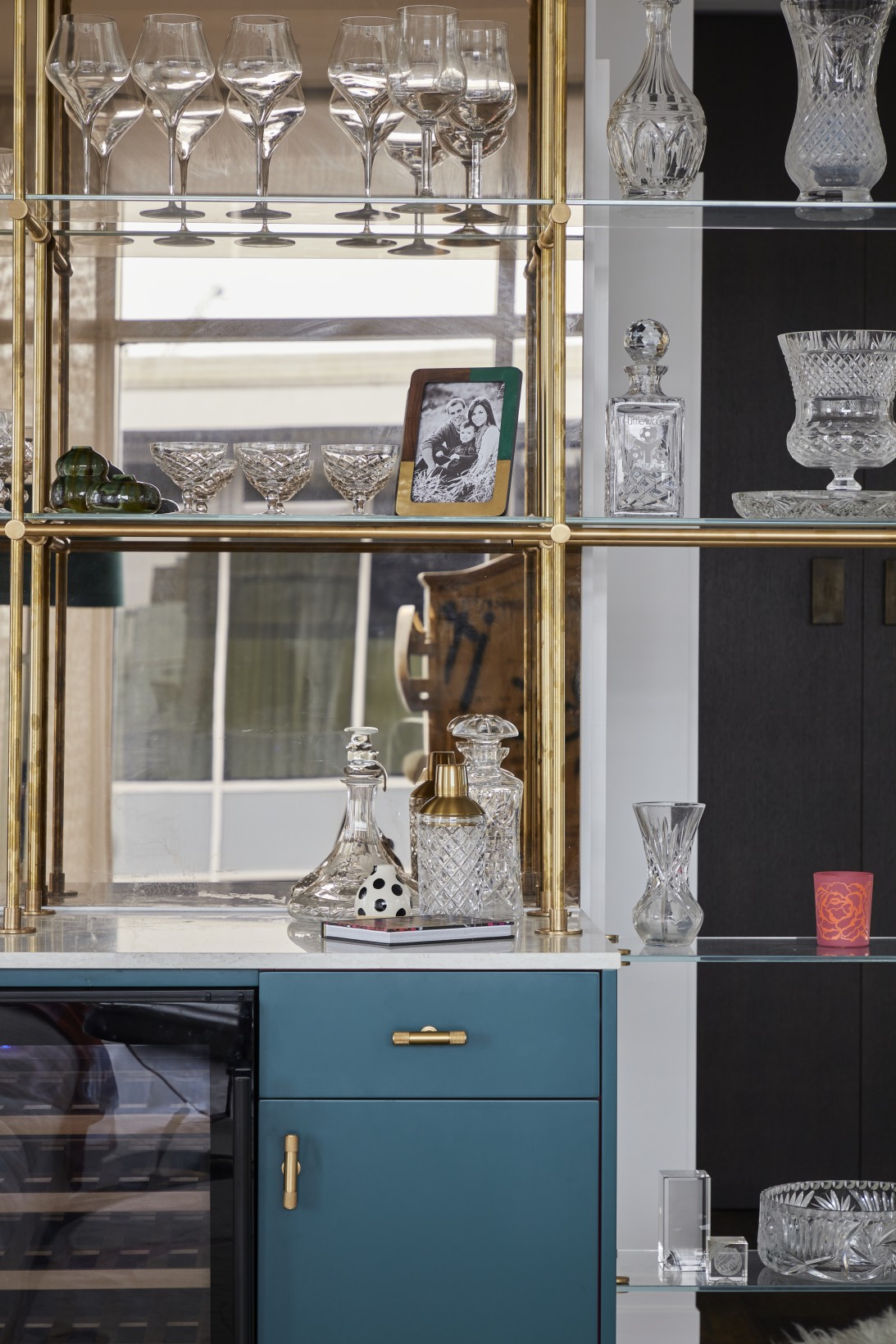 Gold-framed glass shelving with crystal collection in London penthouse party room