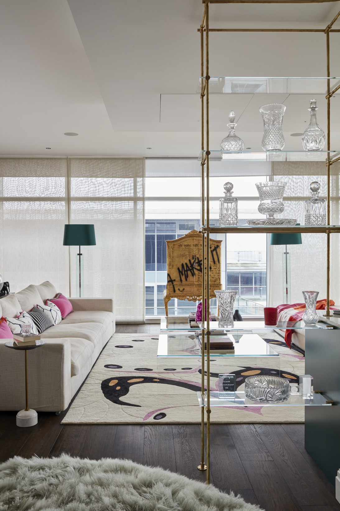Luxury penthouse lounge with glass shelving, crystalware, and teal accents designed by interior designer London