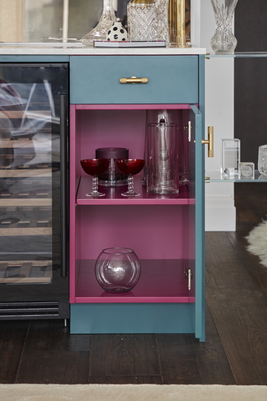 Luxury penthouse bar cabinet with bold pink interior and glassware display