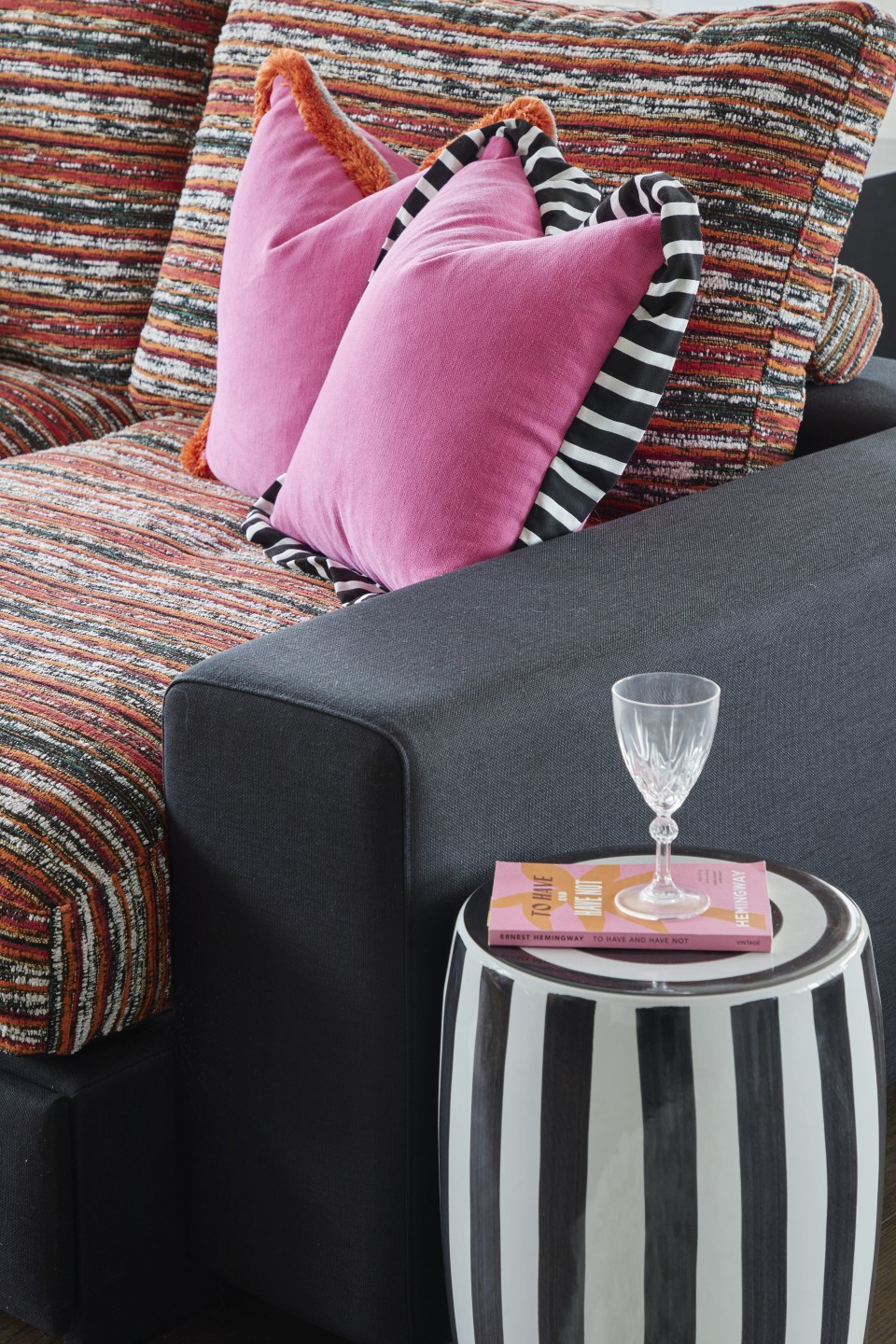 Colourful sofa with pink cushions and striped side table in London penthouse party room