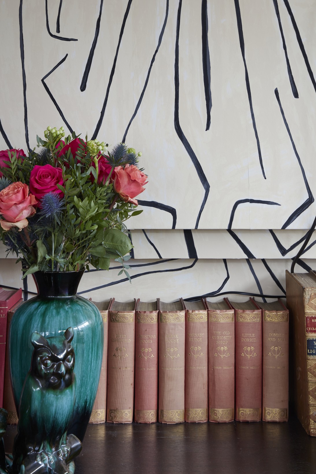 Fireplace shelf with vintage books, green vase, and fresh flowers in London penthouse media room