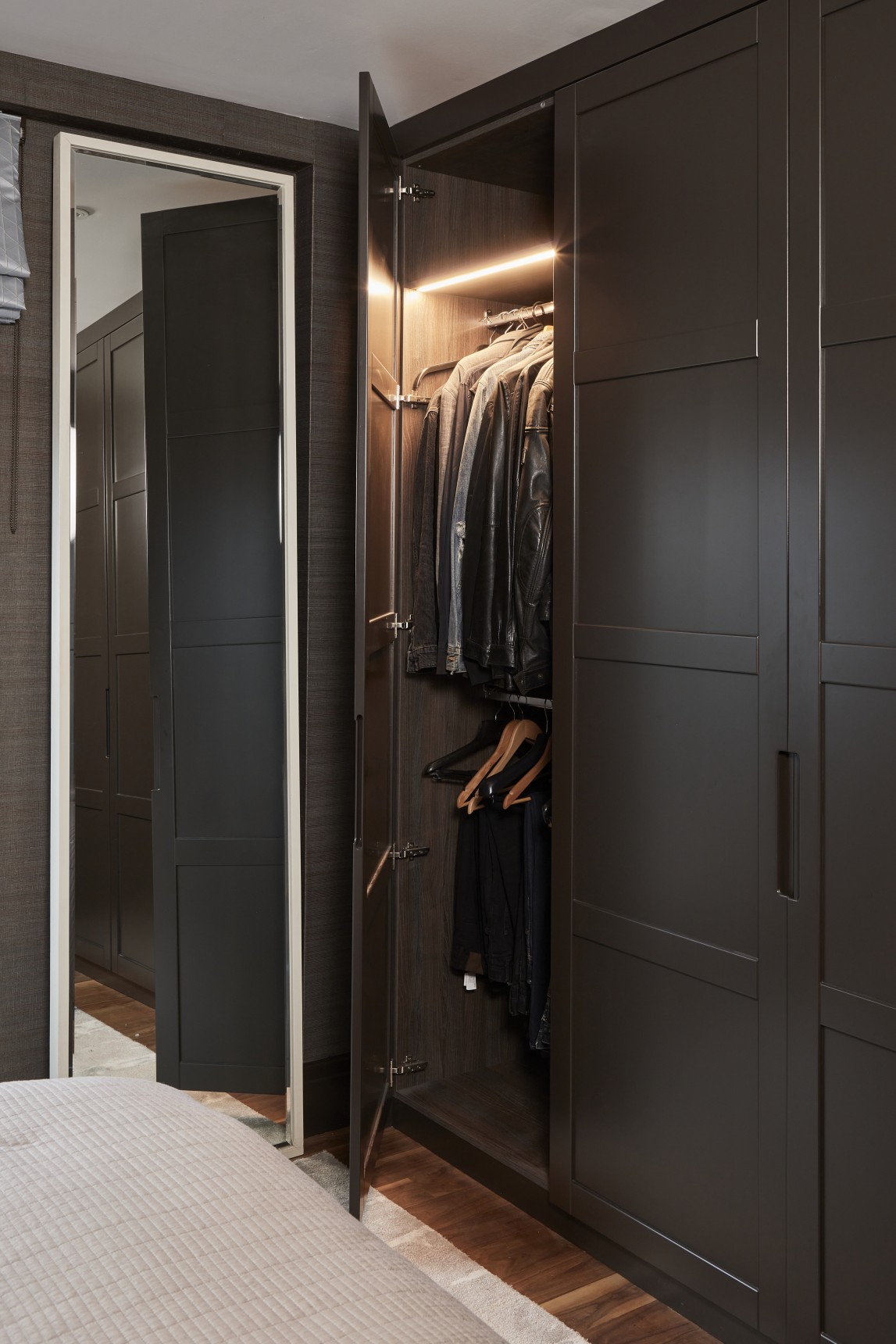 Bespoke wardrobes with integrated lighting in luxury London penthouse master bedroom, designed for stylish storage.