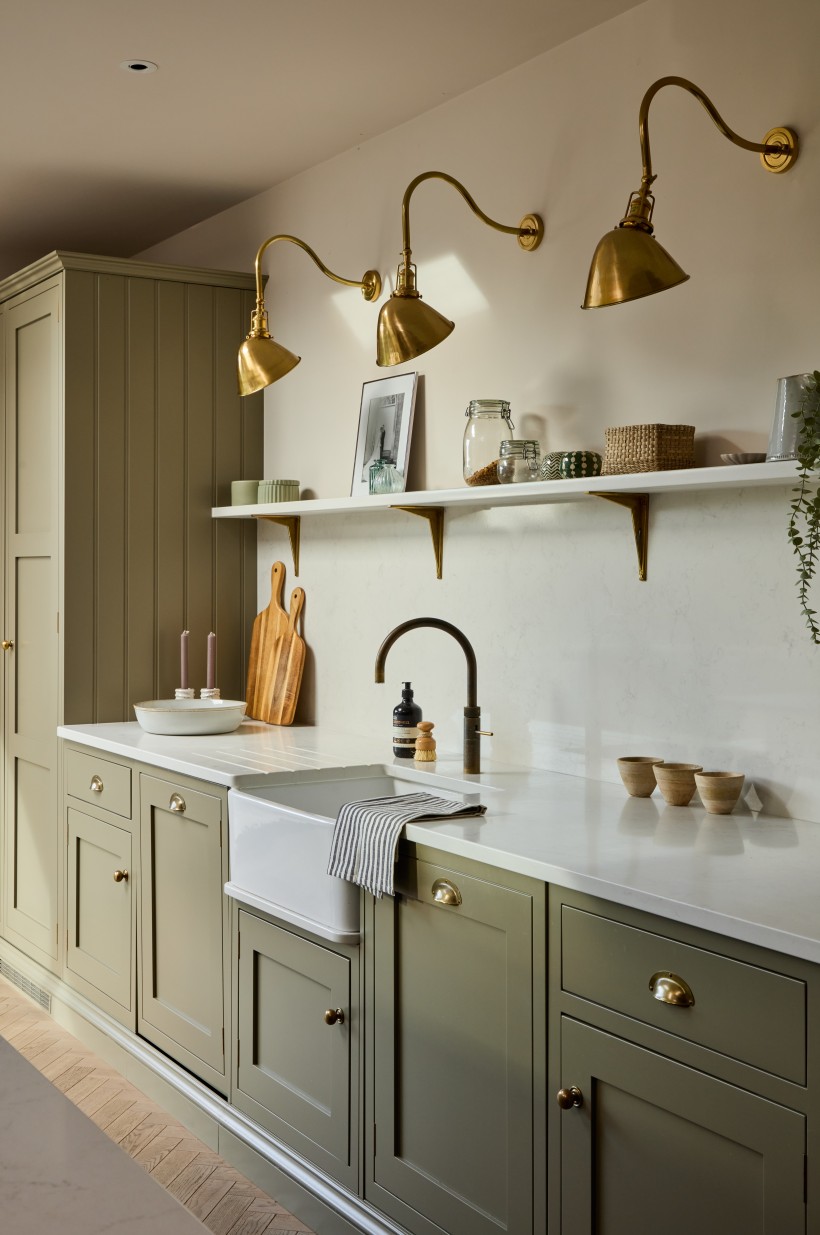 Green shaker kitchen with open shelving brass lighting and butler sink