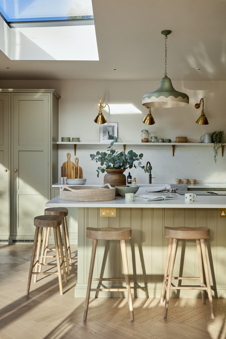 Green kitchen with island pendant lighting and skylight in Cotswolds home