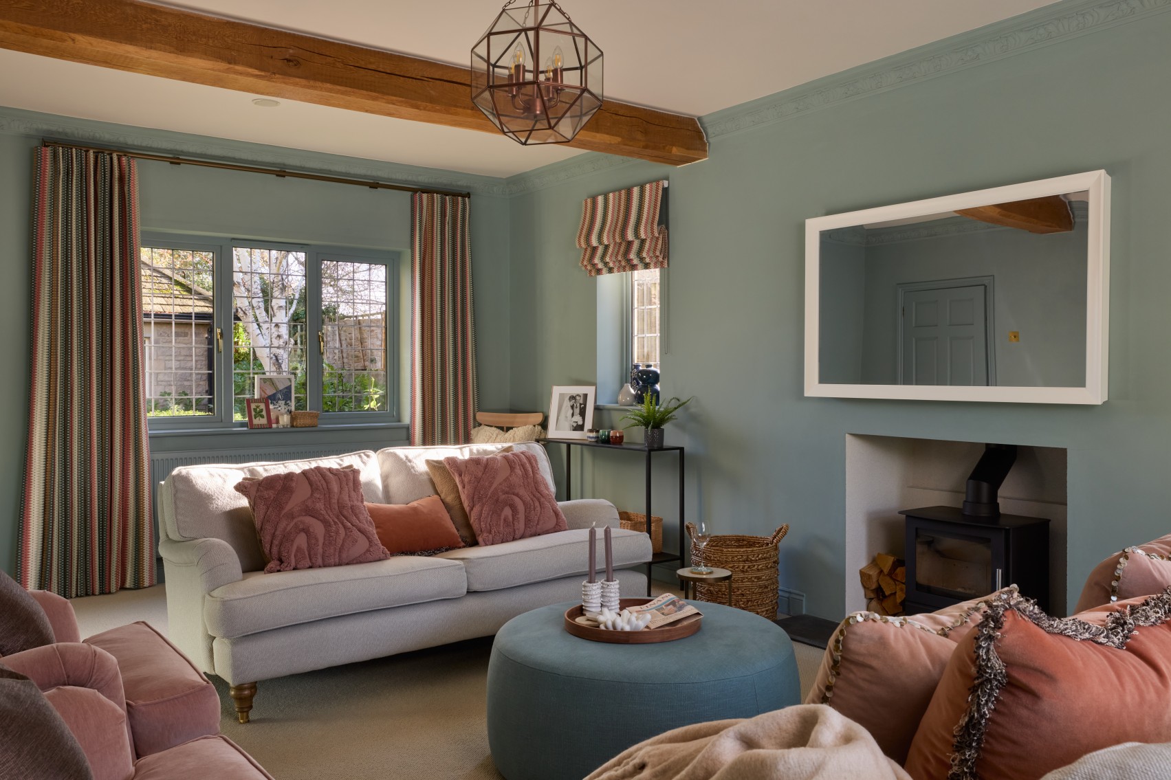 Living room with green walls neutral sofas pink cushions and large ottoman