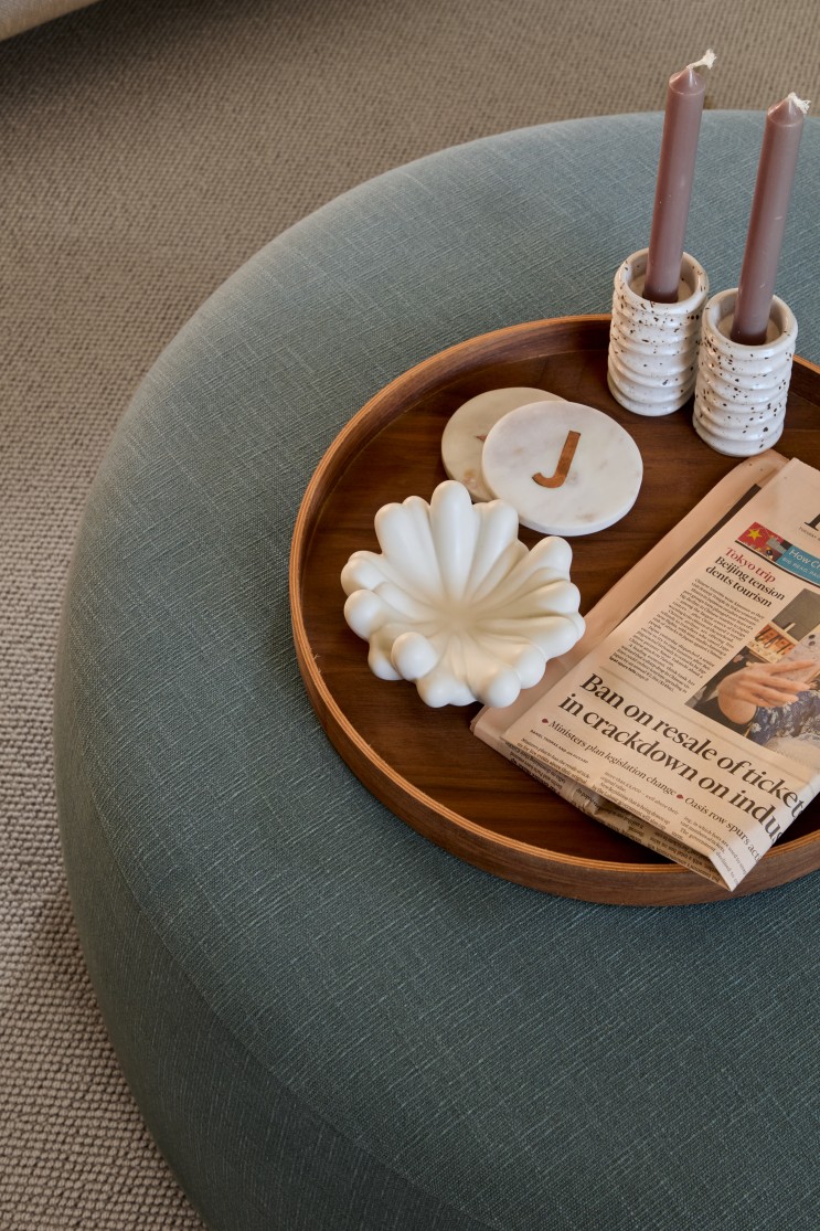 Upholstered ottoman with tray candles and styling detail in living room