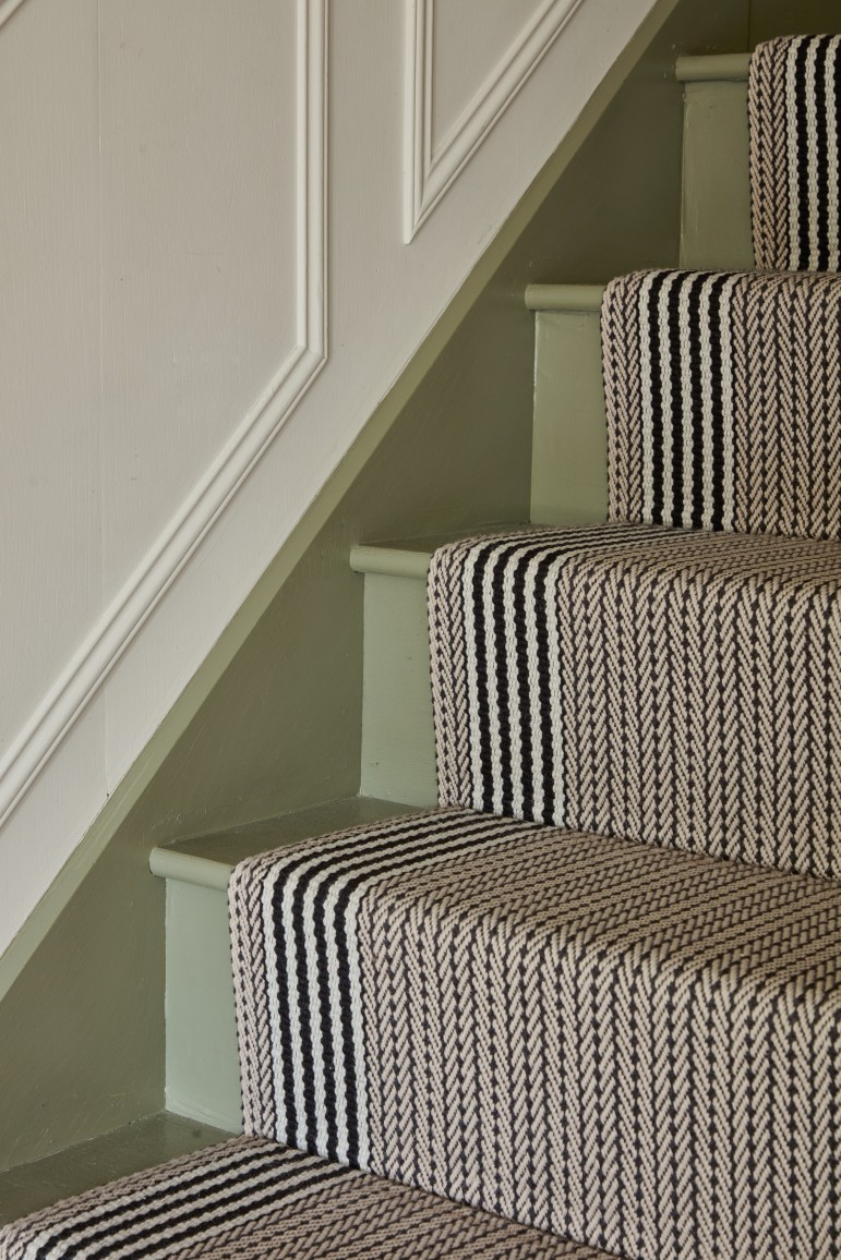 Painted staircase with striped runner and panelling in entrance hall